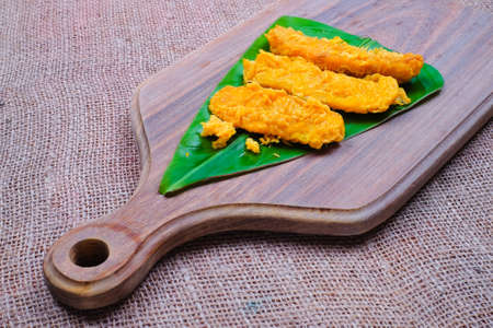 Fried slices of the ripe BANANA also called Pisang Goreng ON BANANA LEAF OVER THE WOODEN CUTTING BOARDの写真素材