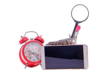 Alarm clock with small shopping cart , handphone and coins isolated on white, limited time shopping...