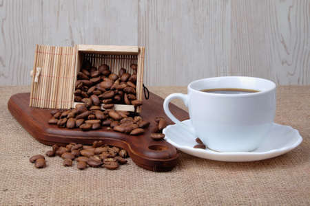Cup of dark coffee with coffee beans on wooden cutting board . Relax time concept.の写真素材