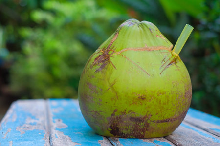 Fresh Coconut with  straw on old wood with blurred background