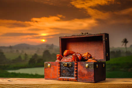 Dates in the decoration box   on old wood with a beautiful sunrise as background. Holy month of Ramadan concept.の写真素材