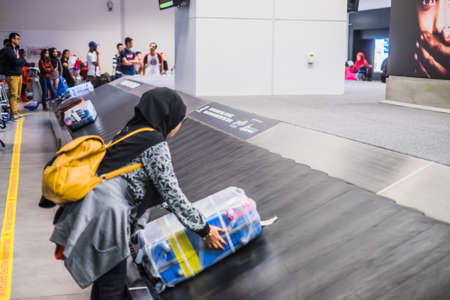 Sepang, Malaysia - Disember 21st, 2017 : Passengers collecting luggage at conveyor belt in Kuala Lumpur International Airport.のeditorial素材