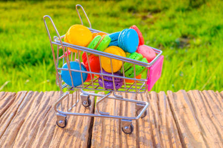 Macarons in small metal shopping cart on green backgroundの写真素材