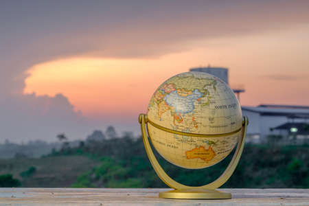 Golden globe on old wood with a beautiful sunrise as background. Travel  Concept.の写真素材