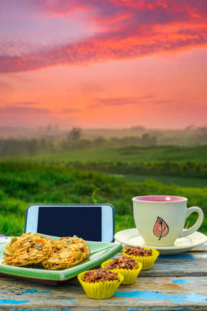 Black coffee cup , smartphone , book and florentine cookies  on wooden table over blurred image of beautiful scenery.の写真素材