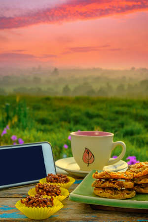 Black coffee cup , smartphone ,chocolate almond ,  and florentine cookies  on wooden table over blurred image of beautiful scenery.の写真素材