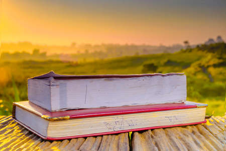 A book and dairy  on wooden table  in the morning during sunrise with green farm and beautiful sunriseの写真素材