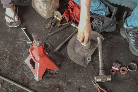Car mechanic repair and replacement of the wheel bearing at the repair service station.