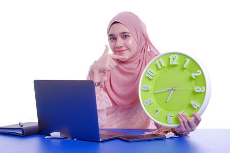 Beautiful young woman in a veil holding a wall clock in her hands isolated on white backgroundの写真素材