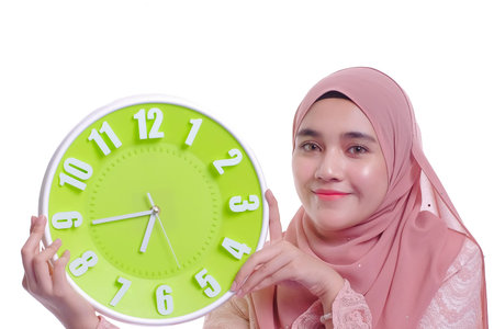 Beautiful young woman in a veil holding a wall clock in her hands isolated on white background