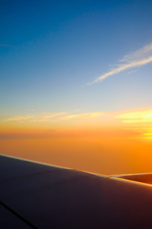 Flying and traveling, view from airplane window on the wing on sunset time