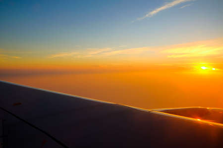 Flying and traveling, view from airplane window on the wing on sunset timeの写真素材