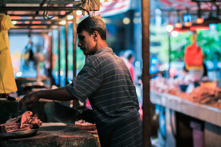 Kuala Lumpur, Malaysia - December 2nd, 2019 :  Malaysian male butchers sell chopped beef meat on the...