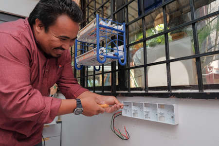 Muadzam Shah, Malaysia - July 12th, 2019 : The hands of an electrician installing a power socket.のeditorial素材