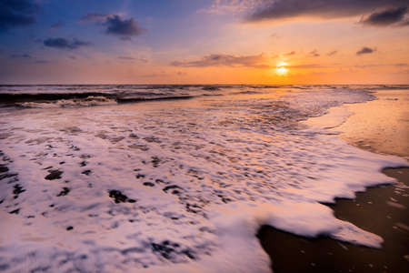 Beautiful cloudscape over the sea with soft wave of blue ocean on sandy beach during sunrise.の写真素材