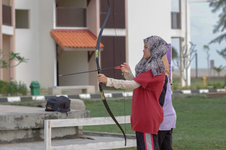 Kuala Rompin, Malaysia- December 29th, 2019 : Outdoor archery range, instructor guiding a  girl ...