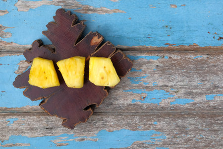 Wooden block with sliced pineapple on wooden table. Top view.