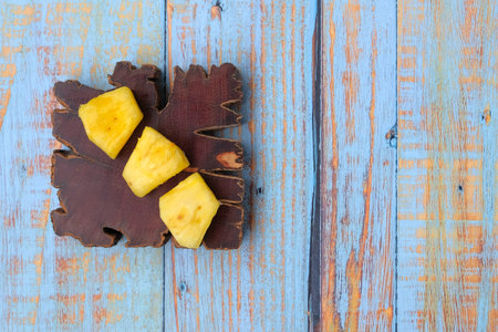 Wooden block with sliced pineapple on wooden table. Top view.