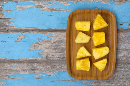 Wooden plate with sliced pineapple on wooden table. Top view.の写真素材