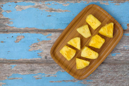 Wooden plate with sliced pineapple on wooden table. Top view.の写真素材