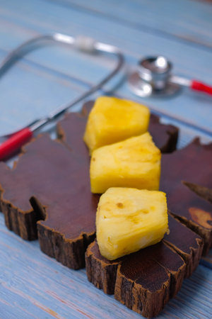 Pineapple sliced and stethoscope on wooden background . Care and healthy concept.