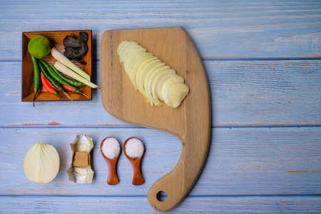 Wooden cutting board   with salt, msg,ginger,garlic,onion,key lime, chilies, chicken stock cube,  and lemongrass over the wooden background.の写真素材