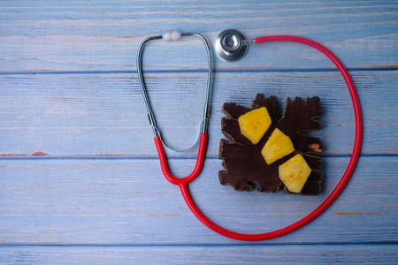 Pineapple sliced and stethoscope on wooden background . Care and healthy concept.