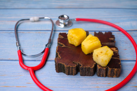 Pineapple sliced and stethoscope on wooden background . Care and healthy concept.