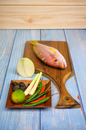 Wooden cutting board   with salt, msg,ginger,garlic,onion,key lime, chilies,  and lemongrass over...