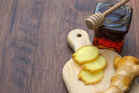 Small jar of honey and   ginger  on wooden background.