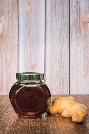 Small jar of honey and   ginger  on wooden background.の写真素材