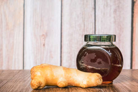 Small jar of honey and   ginger  on wooden background.の写真素材