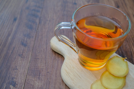 Ginger and  tea  in glass cup at old wooden board in rustic style.