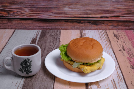 Egg burger  and a cup of tea on wooden background