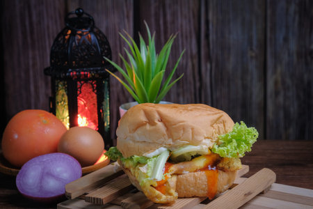 Egg burger, onion, eggs, tomato and lantern  on wooden background