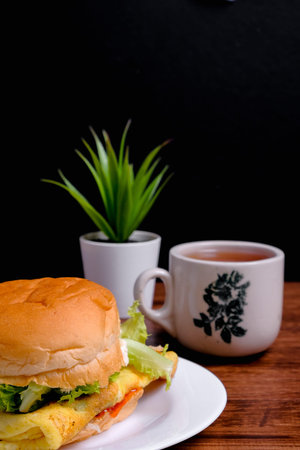Egg burger  and a cup of tea on wooden background