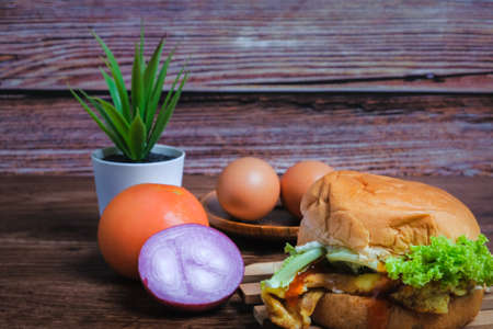 Egg burger , tomato, onion and eggs on wooden backgroundの写真素材