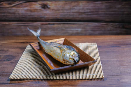 "Cencaru Bakar Sumbat Sambal" in Malay or grilled fish   on a wooden plate on table.の写真素材
