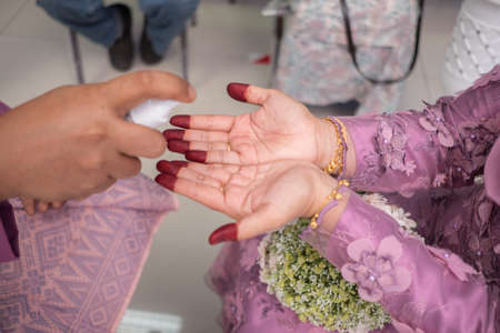 The groom sprayed the disinfectant on the bride's hand during coronavirus pandemic  COVID-19 weddings.のeditorial素材