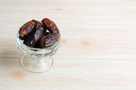 Dried dates in glass bowl on wooden backgroundの写真素材