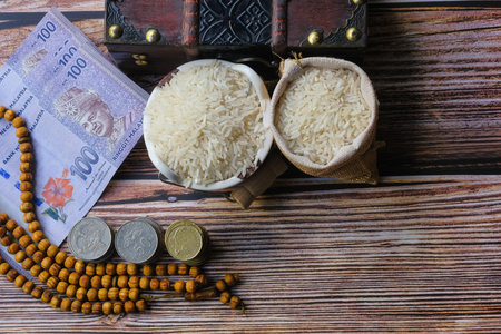 Rice in bucket, money, vintage box,  wooden rosary  on wooden background. Zakat concept