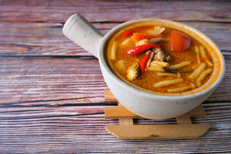 Spicy Thai soup Tom Yum  in claypot on wooden background