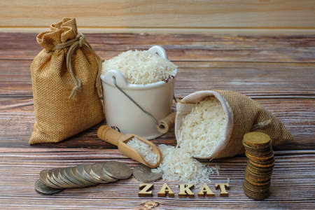 ZAKAT word,  coin stacked  ,  and rice  on wooden background .Zakat Concept.の写真素材
