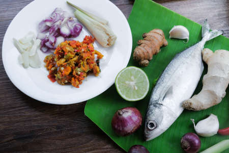 Mackerel with spices to making  Ikan Pepes or grilled fish wrapped in banana leaves on wooden table.の写真素材