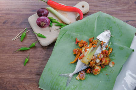 Mackerel with spices to making  Ikan Pepes or grilled fish wrapped in banana leaves on wooden table.の写真素材