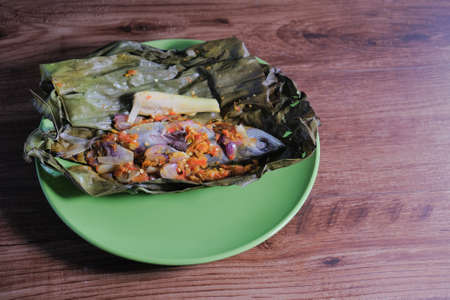 Ikan pepes, grill fish wrapped in banana leaves on green plateの写真素材