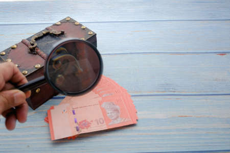 Magnifying glass and a pile of money. Concept of fundraising, attracting investments. Loan to paycheck, urgent loans.の写真素材