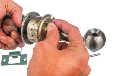 The closeup of worker hands assembling door knob isolated on white background.