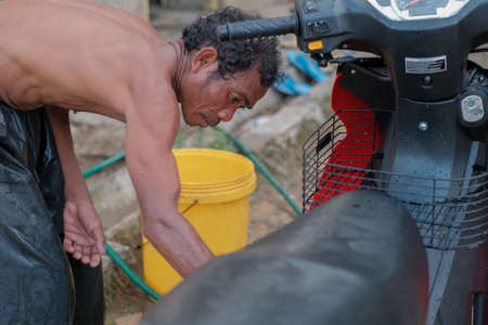 Muadzam Shah, Malaysia - June 17th, 2020 : The Orang Asli (First People) of West Malaysia cleaning and washing his motorcycleのeditorial素材