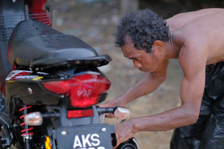Muadzam Shah, Malaysia - June 17th, 2020 : The Orang Asli (First People) of West Malaysia cleaning and washing his motorcycleのeditorial素材